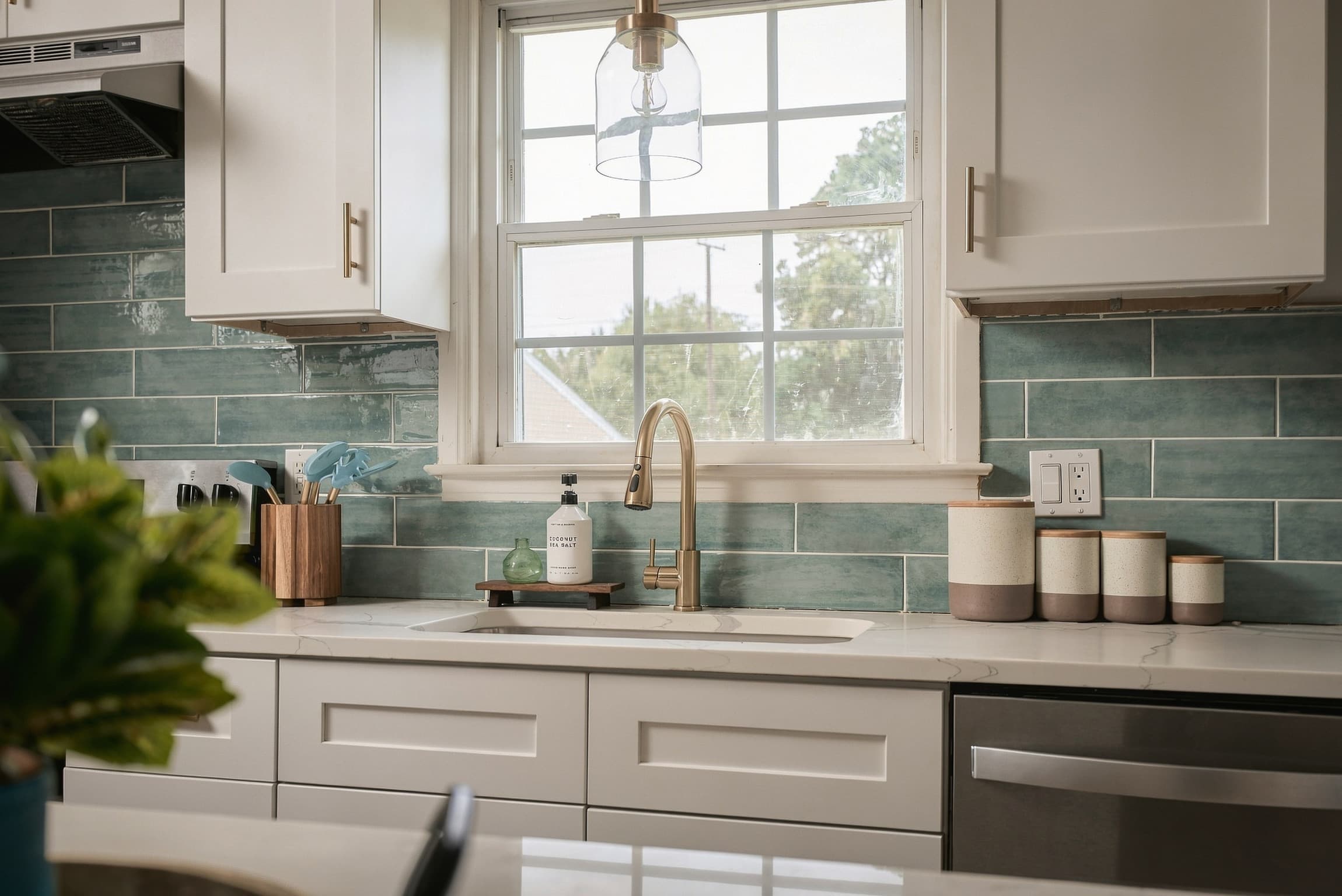 Kitchen sink with a gold faucet under a window