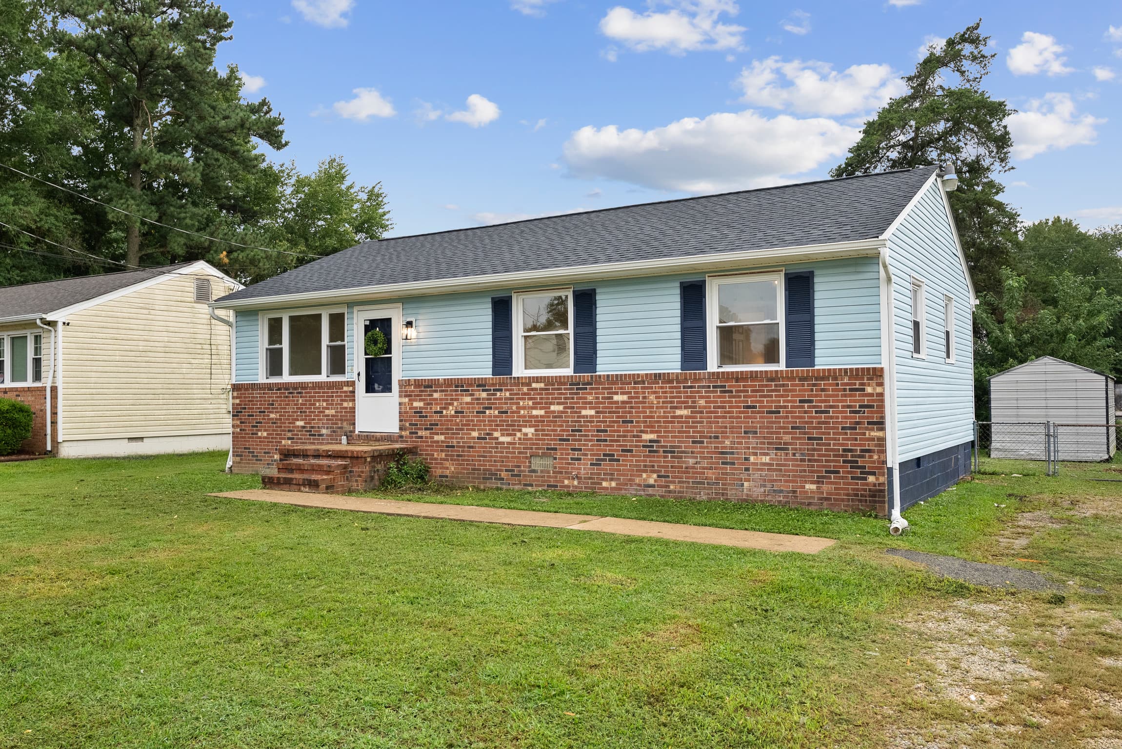 Renovated light-blue brick ranch house with a freshly mowed lawn