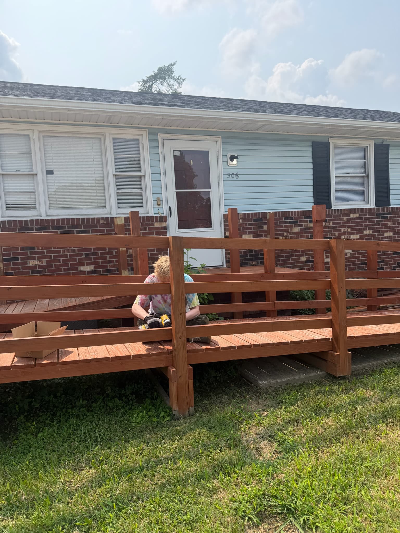 Scott kneeling on the front deck of a house while working on it